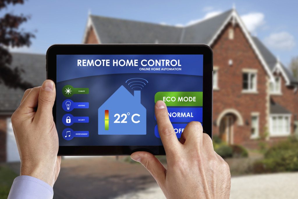 A person is holding an electronic device in front of a house.