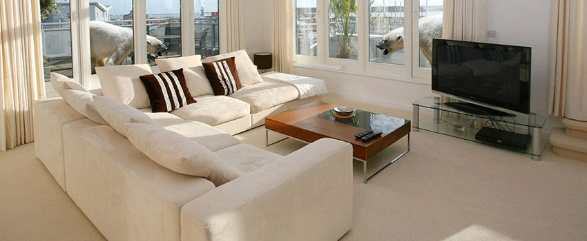 A living room with white furniture and large windows.