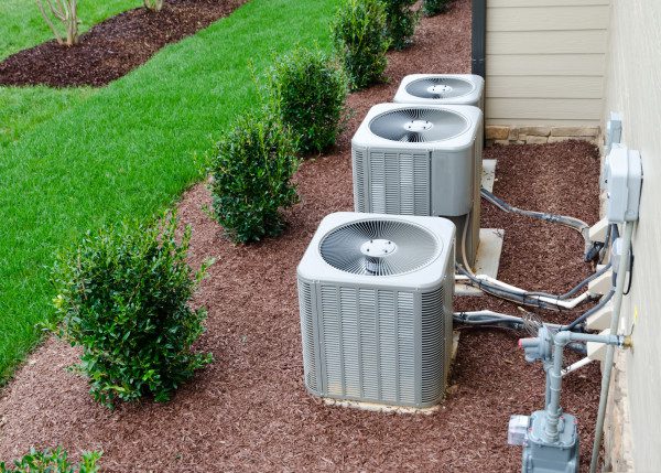 A bunch of air conditioners sitting on top of a lawn.