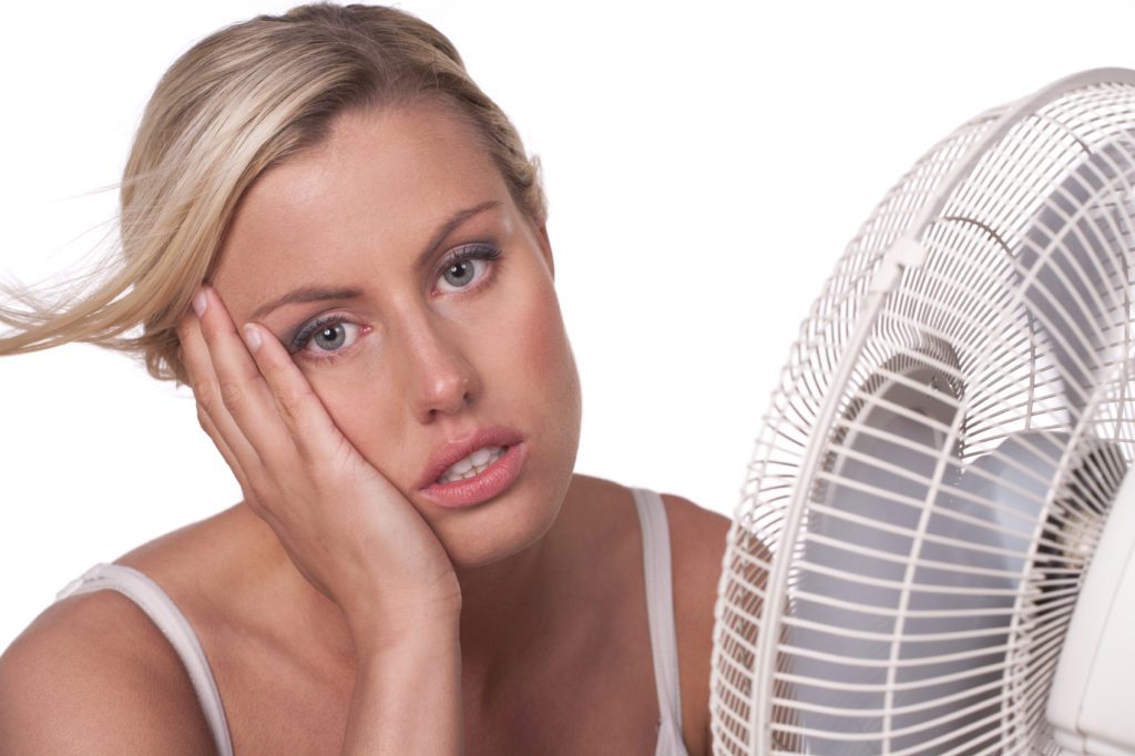 A woman sitting in front of an electric fan.