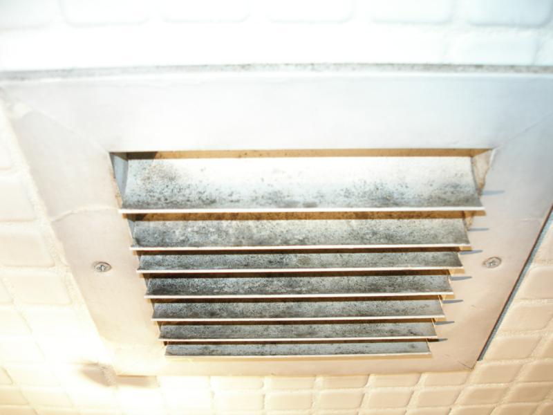 A dirty air vent in the ceiling of an office building.