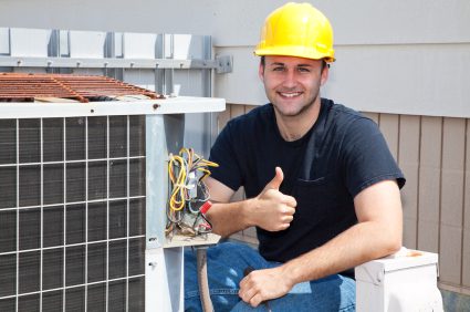 A man in yellow hard hat sitting next to an air conditioner.