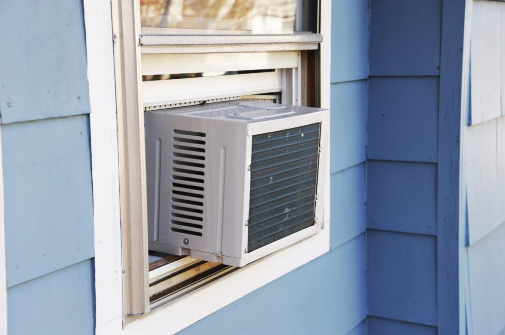 A window air conditioner is mounted on the side of a house.
