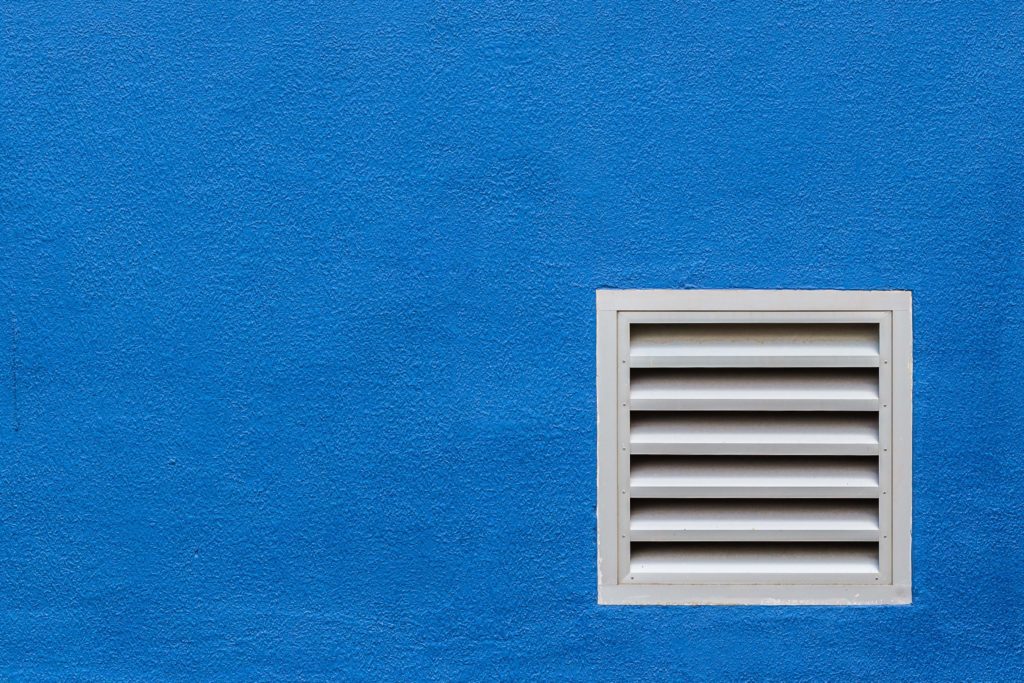 A blue wall with an air vent on it